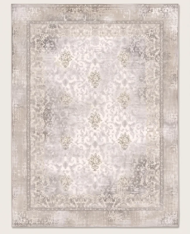 A low-contrast rug covered in small repeating motifs with a soft, faded finish and a light border.
