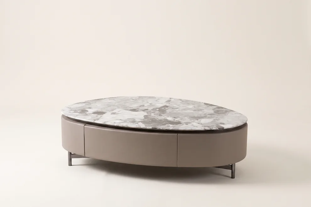 Oval marble-topped coffee table with a low body resting on slim metal legs.